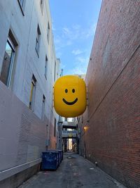 Street light on yellow wall by building against sky