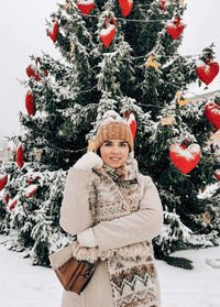 Portrait of woman with christmas tree in background. snow, winter.