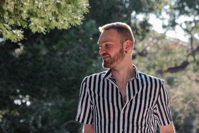 Handsome man wearing striped shirt against trees