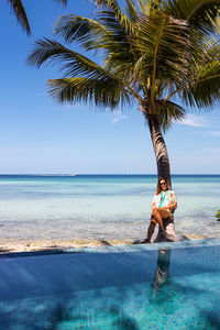 Rear view of woman standing at beach against sky