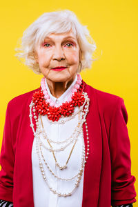 Portrait of senior woman standing against yellow background