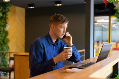 Mid adult man using laptop on table at cafe