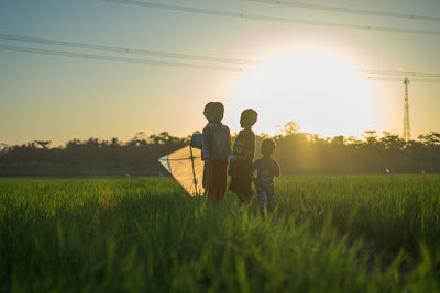 Men standing on field against sky during sunset