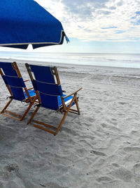 Chairs on beach against sky