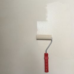 Paint roller on partially painted wall