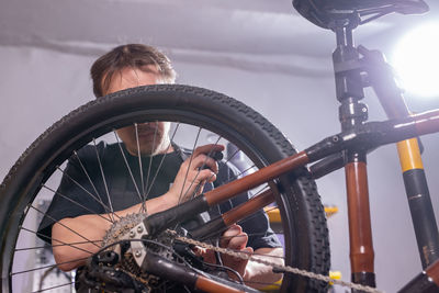 Low angle view of man with bicycle wheel against sky