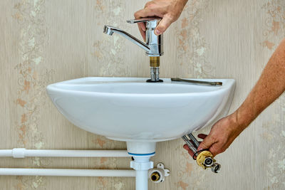 Cropped hand washing hands in bathroom