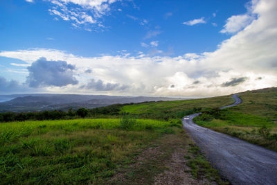 Road amidst field against sky