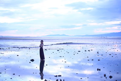 Full length of woman standing on beach against sky