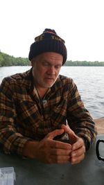 Man sitting on rock against sky