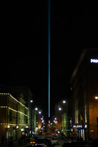 Illuminated street amidst buildings in city at night