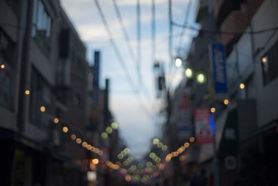 Defocused image of illuminated street lights amidst buildings