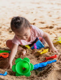 Cute girl playing with toy on sand