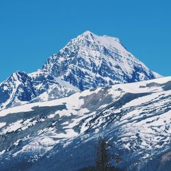 Scenic view of snowcapped mountains against clear blue sky