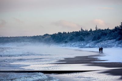 People on shore against sky