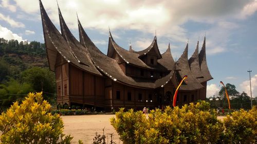 Panoramic view of trees and houses against cloudy sky