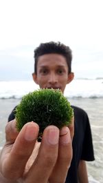 Portrait of man holding ice cream on beach