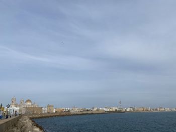 Sea by buildings against sky in city