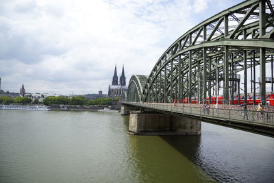 Hohenzollern bridge over rhine river by cologne cathedral against sky