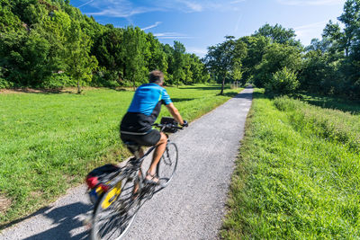 Rear view of man riding bicycle on road