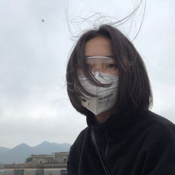 Portrait of woman covering face against sky