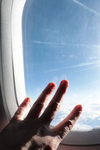 Midsection of person against sky seen through airplane window