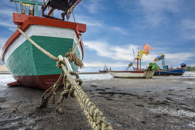 Fishing boats moored at beach against sky