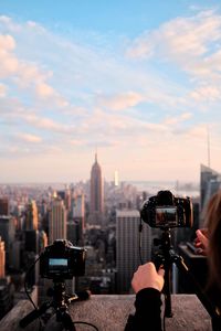 Close-up of woman photographing cityscape against sky