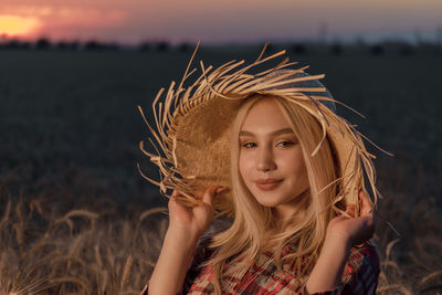 Portrait of smiling girl wearing hat against sky during sunset