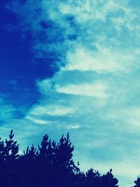 Low angle view of silhouette trees against blue sky