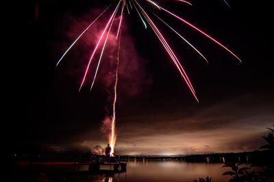 Firework display over river against sky at night