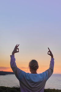 Low angle view of man photographing against clear sky during sunset