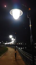 Illuminated street light against sky at night