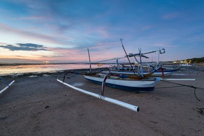 View of boats on beach against cloudy sky
