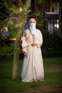 Portrait of woman standing against trees