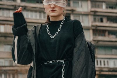 Midsection of woman with blindfold standing against building