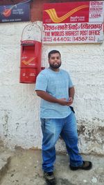 Portrait of young man standing against wall