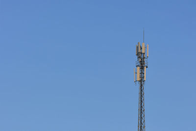 Low angle view of communications tower against blue sky