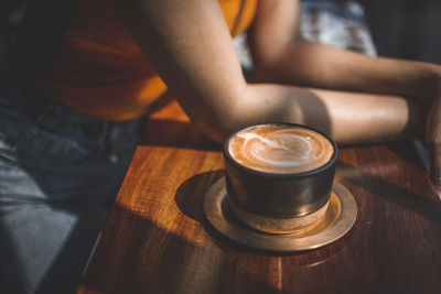 Midsection of woman with coffee cup at table