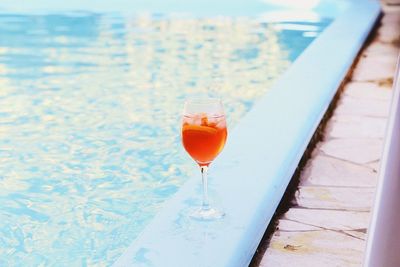 Close-up of wineglass on table by swimming pool