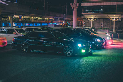 Cars on illuminated city street at night