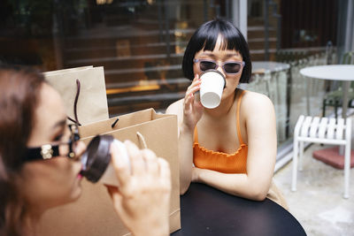 Lesbian woman holding disposable coffee cup sitting at cafe