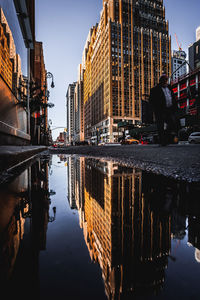 Reflection of buildings in puddle on street