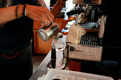 Midsection of man preparing coffee in cup