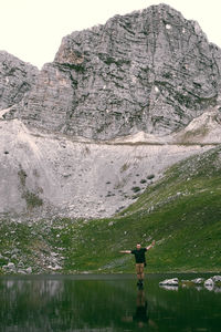 Man on rock by lake against mountain