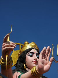 Low angle view of woman holding camera against clear blue sky