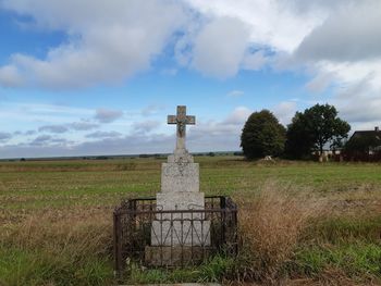 Cross on field against sky