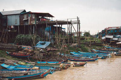 Fishing boats moored at harbor against abandoned houses