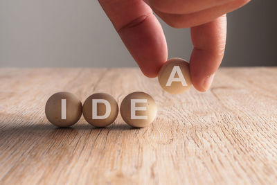 Cropped hand arranging balls with idea text on wooden table