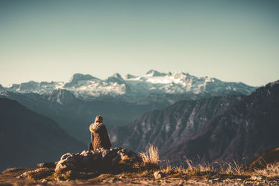 Man sitting on rock against mountains